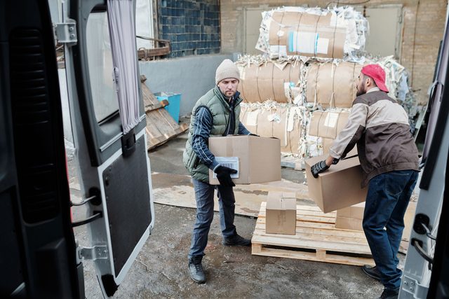 Twee mannen laden dozen in een wagen