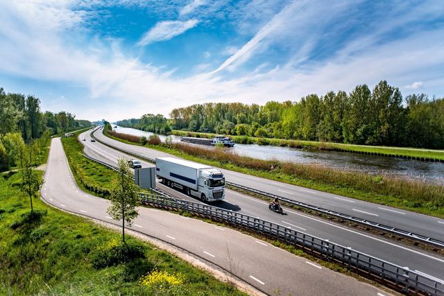 Een vrachtwagen met oplegger op een snelweg langs een kanaal